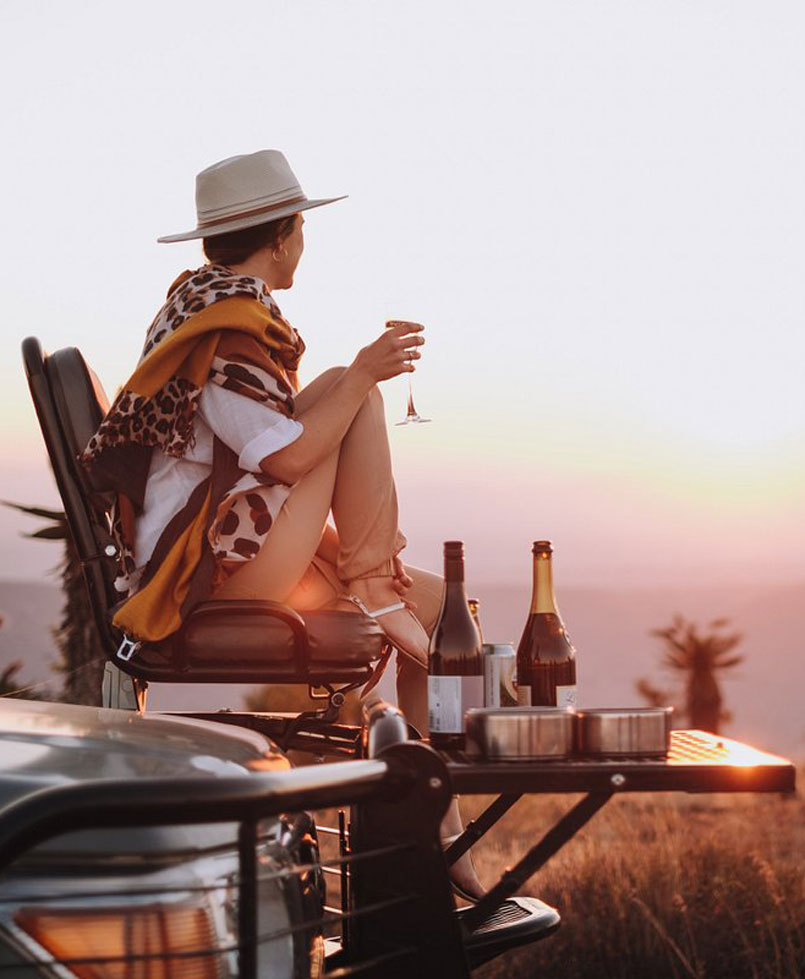 Woman sitting on safari vehicle in the sunset.