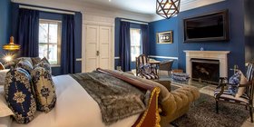 Luxury suite bedroom with bold blue decor, gold-framed bed and fireplace at Fairlawns Boutique Hotel and Spa, Johannesburg
