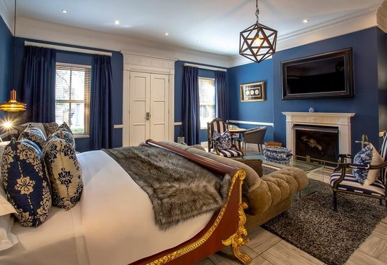 Luxury suite bedroom with bold blue decor, gold-framed bed and fireplace at Fairlawns Boutique Hotel and Spa, Johannesburg