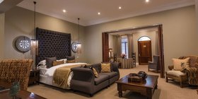 Spacious luxury villa bedroom with dramatic tufted headboard and African art at Fairlawns Boutique Hotel and Spa, Johannesburg