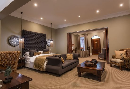 Spacious luxury villa bedroom with dramatic tufted headboard and African art at Fairlawns Boutique Hotel and Spa, Johannesburg