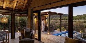 Candlelit bedroom chalet interior opening onto a private pool deck at dusk at Kwandwe Great Fish River Lodge, Eastern Cape, South Africa