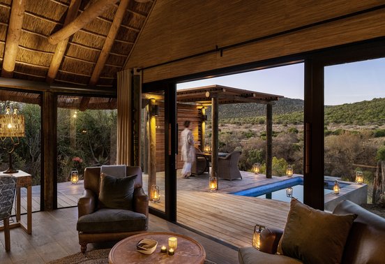 Candlelit bedroom chalet interior opening onto a private pool deck at dusk at Kwandwe Great Fish River Lodge, Eastern Cape, South Africa