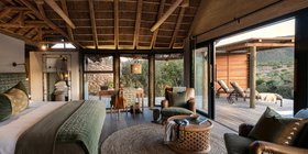 Luxury thatched bedroom suite with king bed, leather armchairs and private deck with bush views at Kwandwe Great Fish River Lodge, Eastern Cape
