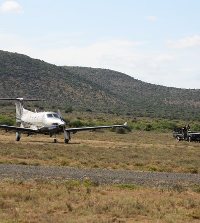 Private aircraft landing at Kwandwe Private Game Reserve airstrip with safari vehicles awaiting guests, Eastern Cape, South Africa