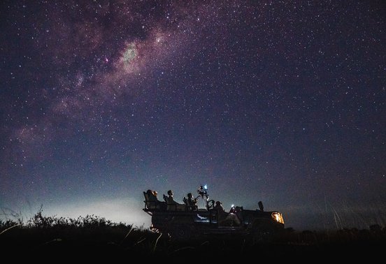 Guests silhouetted in a safari vehicle beneath the Milky Way galaxy in Phinda Private Game Reserve, South Africa