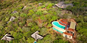 Aerial view of andBeyond Phinda Mountain Lodge showing thatched suites, communal pool and bush setting in KwaZulu-Natal, South Africa
