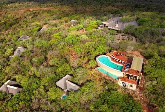 Aerial view of andBeyond Phinda Mountain Lodge showing thatched suites, communal pool and bush setting in KwaZulu-Natal, South Africa