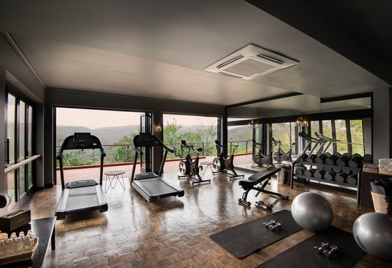 Well-equipped gym with floor-to-ceiling windows and panoramic bush views at andBeyond Phinda Mountain Lodge, KwaZulu-Natal