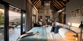 Luxury suite bedroom with thatched ceiling, king bed and private pool deck overlooking Phinda's hills at andBeyond Phinda Mountain Lodge