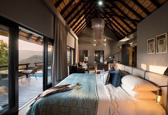 Luxury suite bedroom with thatched ceiling, king bed and private pool deck overlooking Phinda's hills at andBeyond Phinda Mountain Lodge