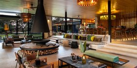 Stylish open-plan lounge and bar area with fireplace and designer lighting at Tanda Tula Safari Camp, Timbavati