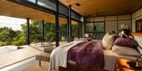 Luxury suite bedroom with floor-to-ceiling glass walls overlooking the Timbavati bush at Tanda Tula Safari Camp