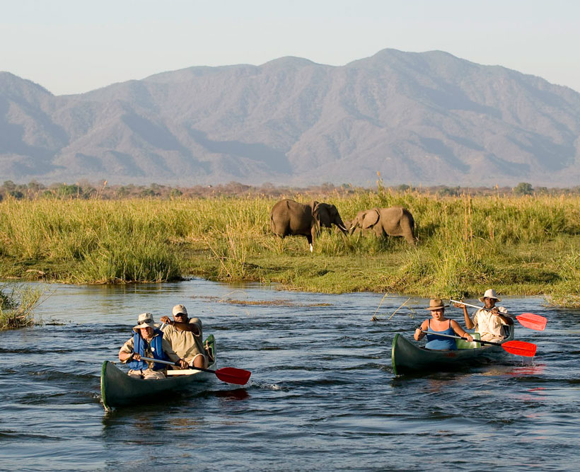 People on safari on the river with elephants.