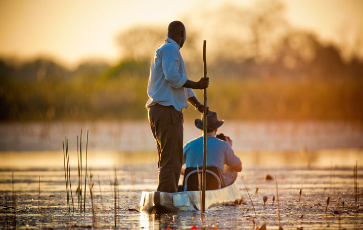 Man on a mokoro being guided on safari.