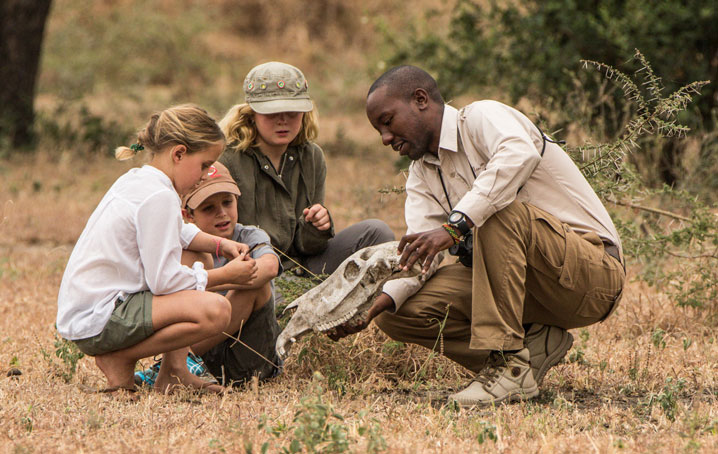 Guide showing kids a skull in the bush.