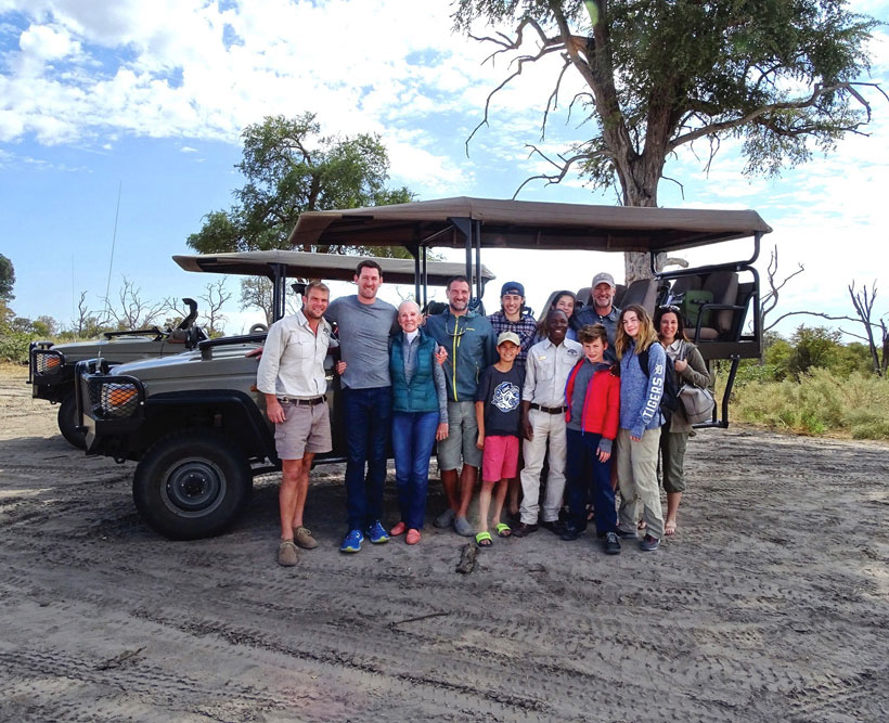 A family of travelers in front of their safari vehicle.
