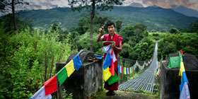A man standing next to the bridge leading into Punakha