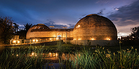 Architectural domes of Ila Safari Lodge glowing at dusk beside the Kafue River, Zambia.