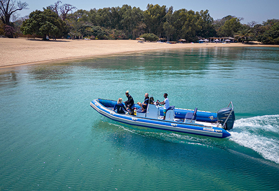 Guests arriving by speedboat over crystal-clear water to the sandy shores of Likoma Island, Malawi.