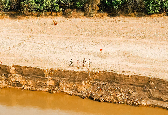 Guests on a guided walking safari along the sandy banks of the Luangwa River in South Luangwa National Park, Zambia.