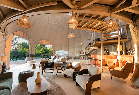 Open-air lounge of Ila Safari Lodge featuring modern eco-luxury design and natural textures overlooking the bush.
