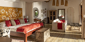 Spacious Garden House bedroom with handcrafted Zambian décor and warm natural light at Tongabezi Lodge.