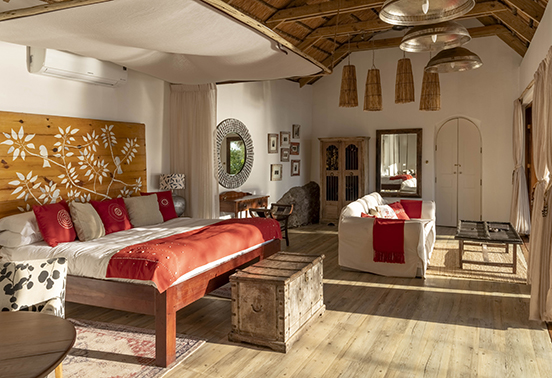 Spacious Garden House bedroom with handcrafted Zambian décor and warm natural light at Tongabezi Lodge.