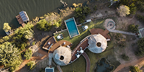 Aerial view of Ila Safari Lodge showing solar-powered domes, pool, and Kafue River setting.