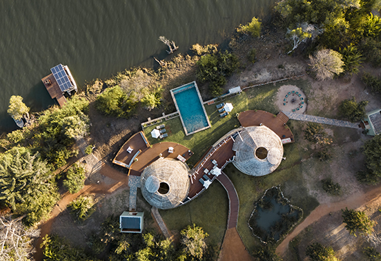 Aerial view of Ila Safari Lodge showing solar-powered domes, pool, and Kafue River setting.