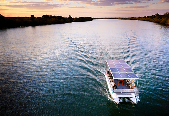 Solar-powered safari boat cruising along the Kafue River at sunset from Ila Safari Lodge, Zambia.
