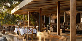 Open-air dining deck and lounge at Sausage Tree Camp overlooking the Zambezi River in Lower Zambezi National Park, Zambia.