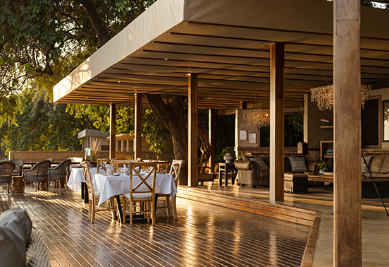 Open-air dining deck and lounge at Sausage Tree Camp overlooking the Zambezi River in Lower Zambezi National Park, Zambia.