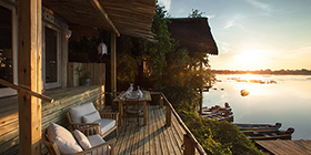 River Cottage deck at Tongabezi Lodge overlooking the Zambezi River at sunrise.