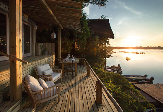 River Cottage deck at Tongabezi Lodge overlooking the Zambezi River at sunrise.