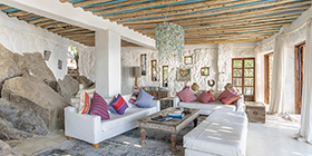 Lounge at Kaya Mawa featuring handcrafted furnishings, beaded chandelier, and natural rock walls.