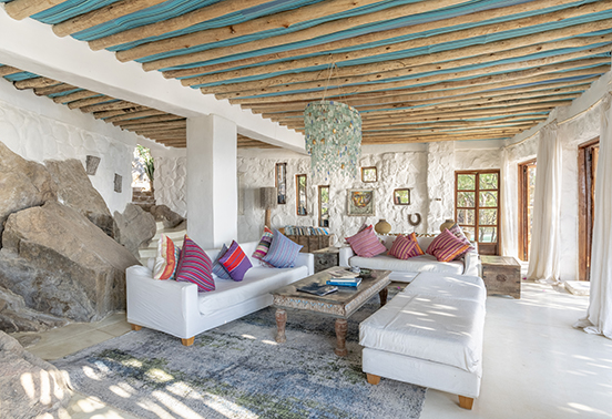 Lounge at Kaya Mawa featuring handcrafted furnishings, beaded chandelier, and natural rock walls.