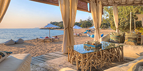 Beachfront lounge at Kaya Mawa overlooking golden sands and Lake Malawi at sunset.