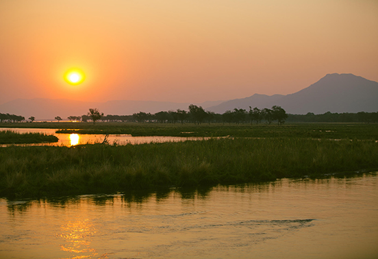 Golden sunset over the Zambezi River with reflections on the water and distant escarpment, Lower Zambezi National Park.