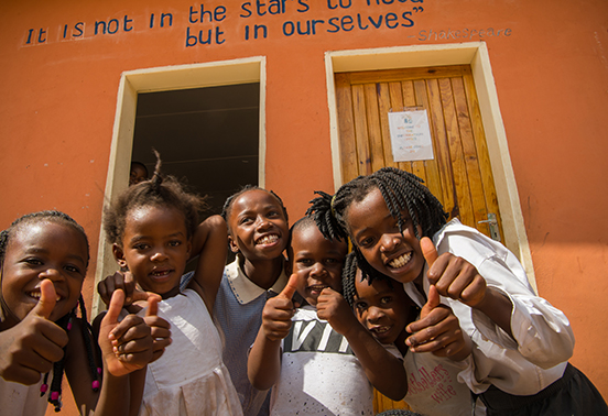 Smiling students giving thumbs up outside Tujatane School, supported by Tongabezi Lodge, Livingstone, Zambia.