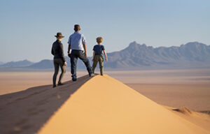 Standing on a sand dune overlooking a vast desert landscape and distant mountains in Namibia.