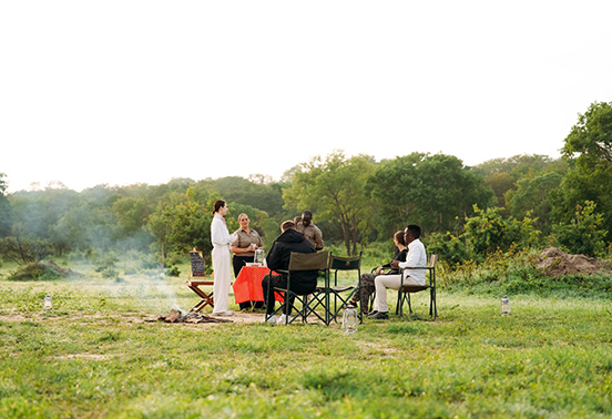 Guests enjoying an outdoor safari dining experience at Iganyana Tented Camp in Hwange