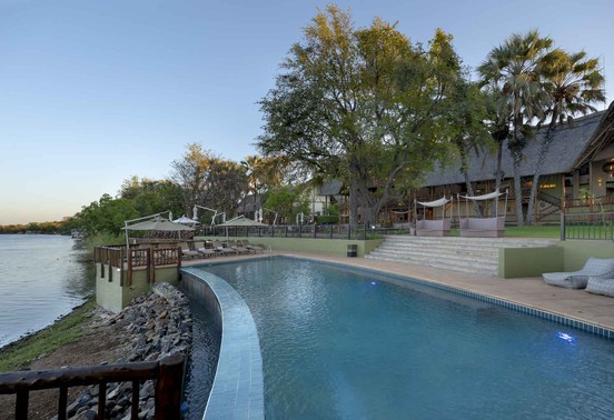 Swimming pool and sun deck overlooking the Zambezi River at dusk at David Livingstone Safari Lodge, Livingstone, Zambia