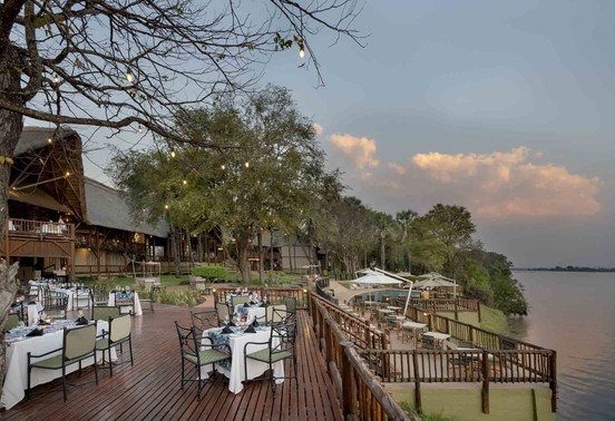 Candlelit outdoor dining deck set for dinner on the banks of the Zambezi River at David Livingstone Safari Lodge, Livingstone, Zambia