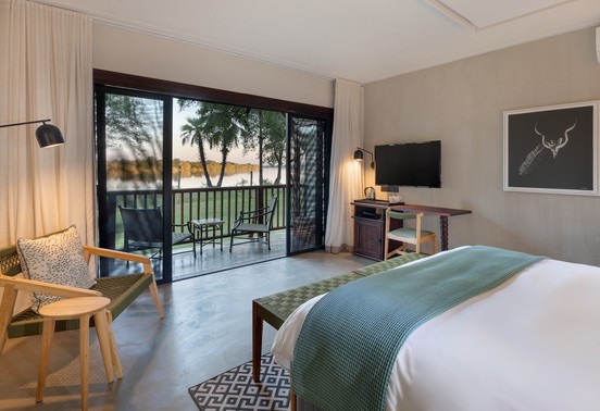 Modern king bedroom with floor-to-ceiling Zambezi river views and private balcony at David Livingstone Safari Lodge, Zambia