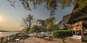 Golden sunset over the Zambezi riverfront gardens and thatched lodge at David Livingstone Safari Lodge, Livingstone, Zambia