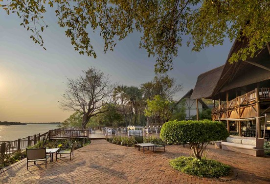 Golden sunset over the Zambezi riverfront gardens and thatched lodge at David Livingstone Safari Lodge, Livingstone, Zambia