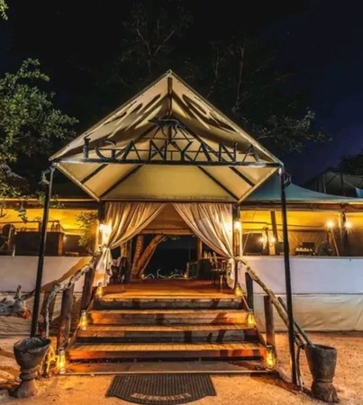 Illuminated entrance to Iganyana Tented Camp at night with warm lantern light and canvas tent, Hwange, Zimbabwe
