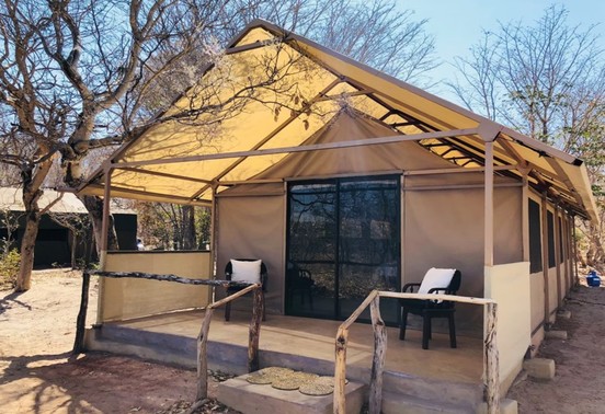 Canvas safari tent with private veranda amid acacia woodland at Iganyana Tented Camp, Hwange, Zimbabwe