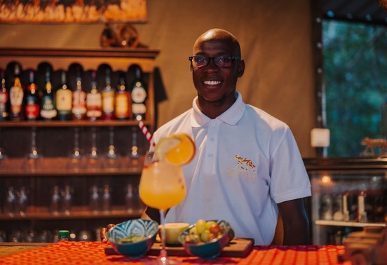 Iganyana Tented Camp bartender serving a tropical cocktail at the safari bar, Zimbabwe